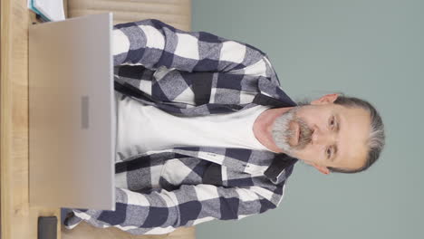 Vertical-video-of-Old-man-closing-laptop-with-angry-expression.